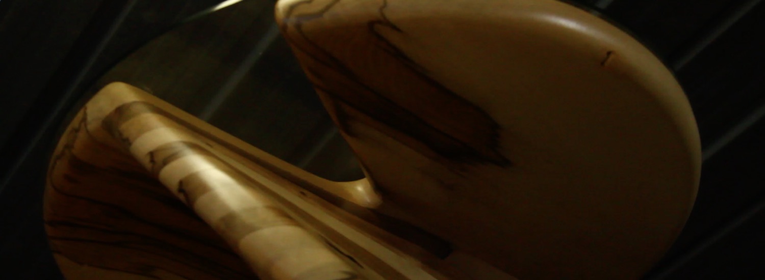 Occasional tables curved in a helix and made from laminated black heart sassafras with a gleaming glass top (view from below).