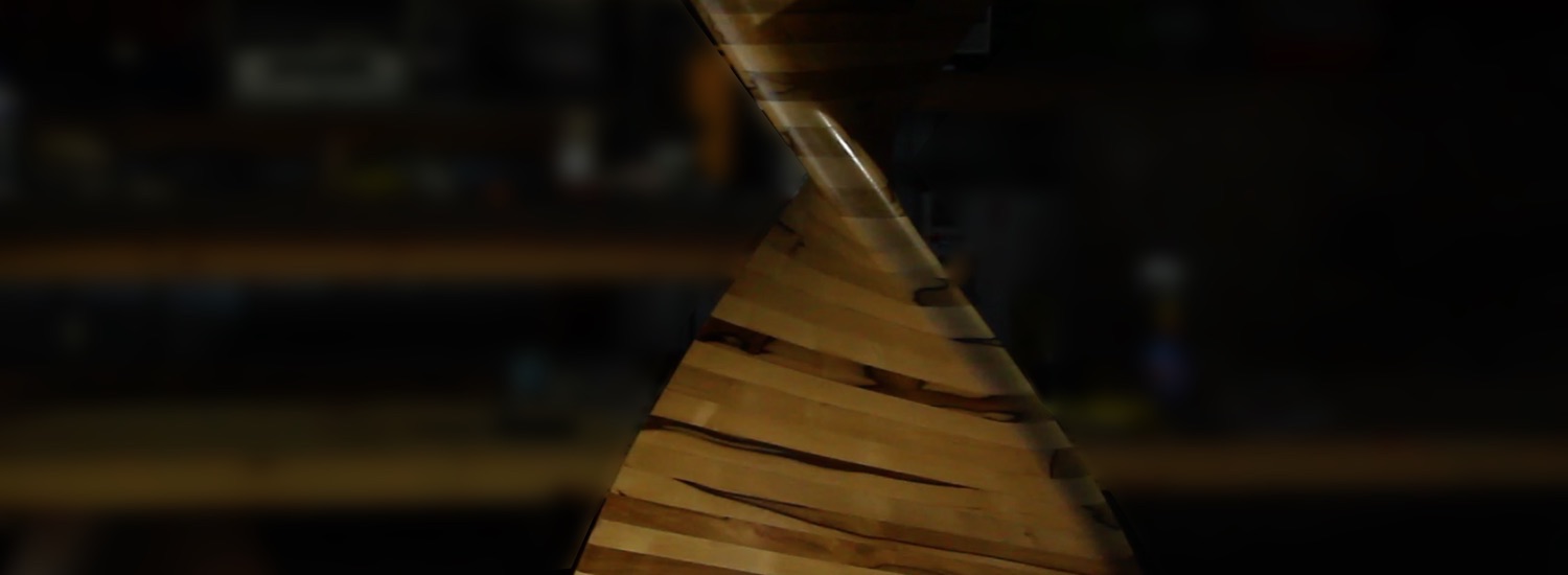 Occasional tables curved in a helix and made from laminated black heart sassafras with a gleaming glass top (close-up of the stand).